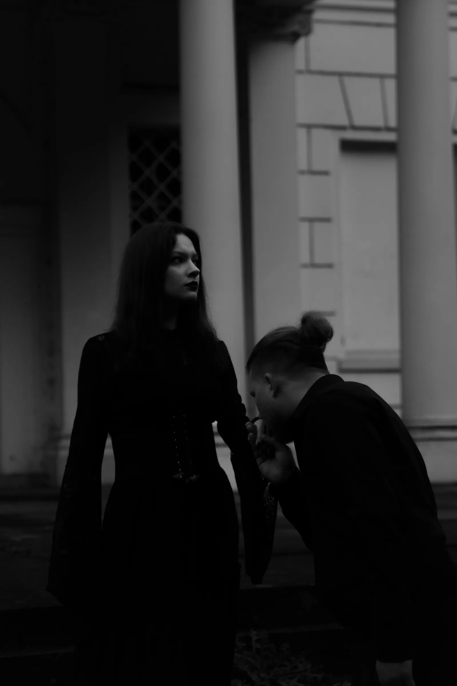 Mężczyzna całuje dłoń kobiety przed klasycystyczną kolumnadą