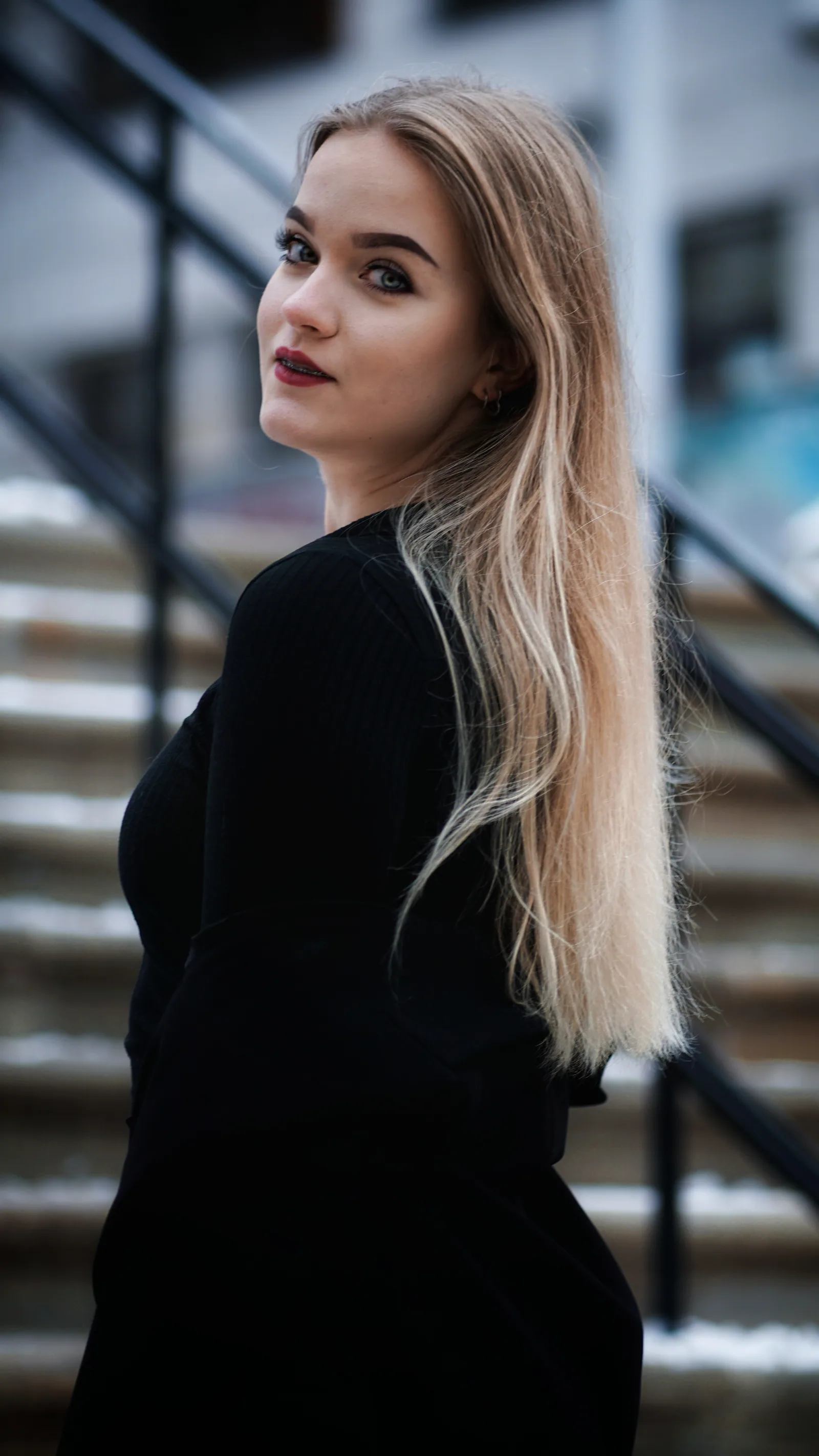 Portret kobiety przy metalowej barierce, zimowe światło